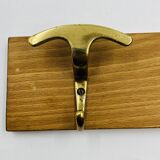 Vintage wall coat rack in brass and wood design.