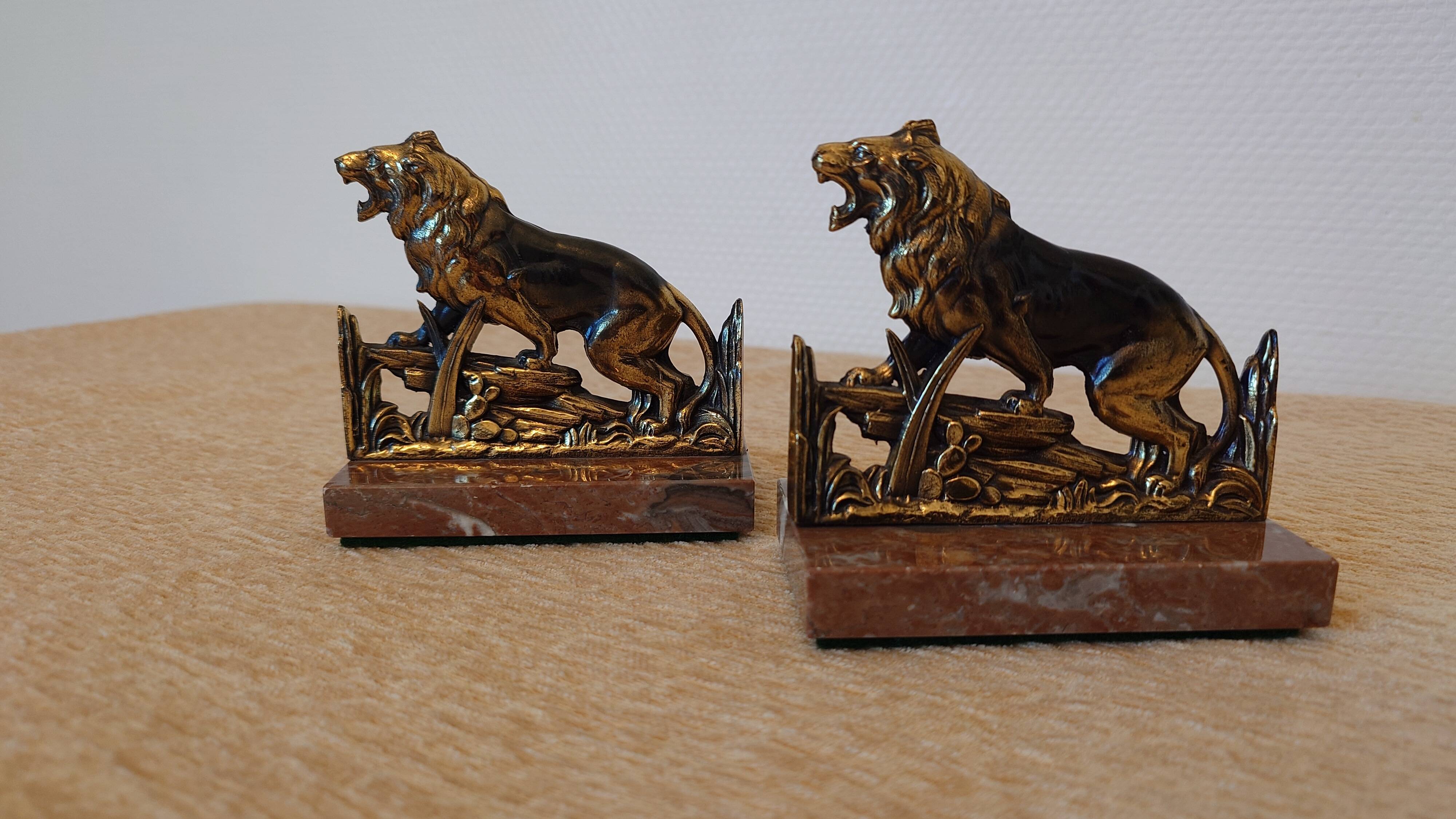Small roaring lion bookends in patinated metal on a marble base.