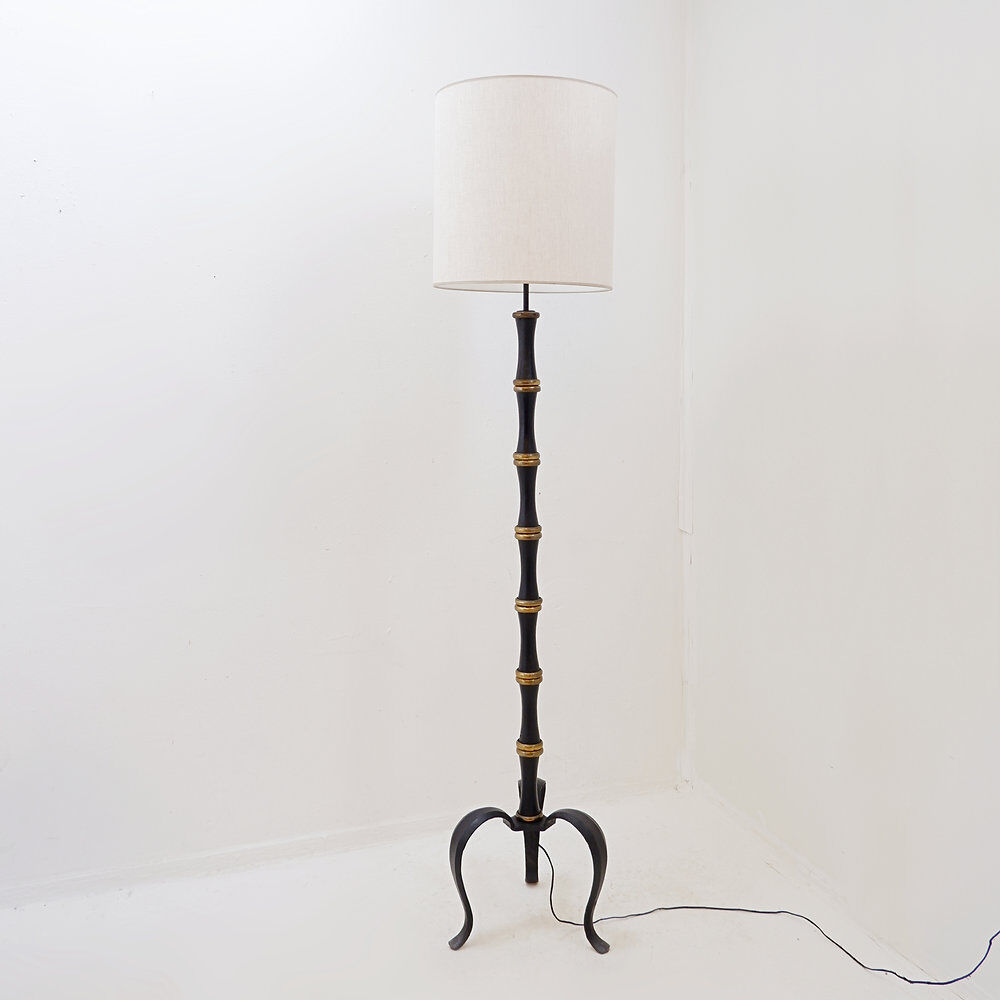 Tripod floor lamp in wrought iron and brass with bamboo-style base.