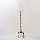 Tripod floor lamp in wrought iron and brass with bamboo-style base.