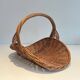 Woven Rattan Log Holder in a Semi-Round Shape with a Central Arched Handle.
