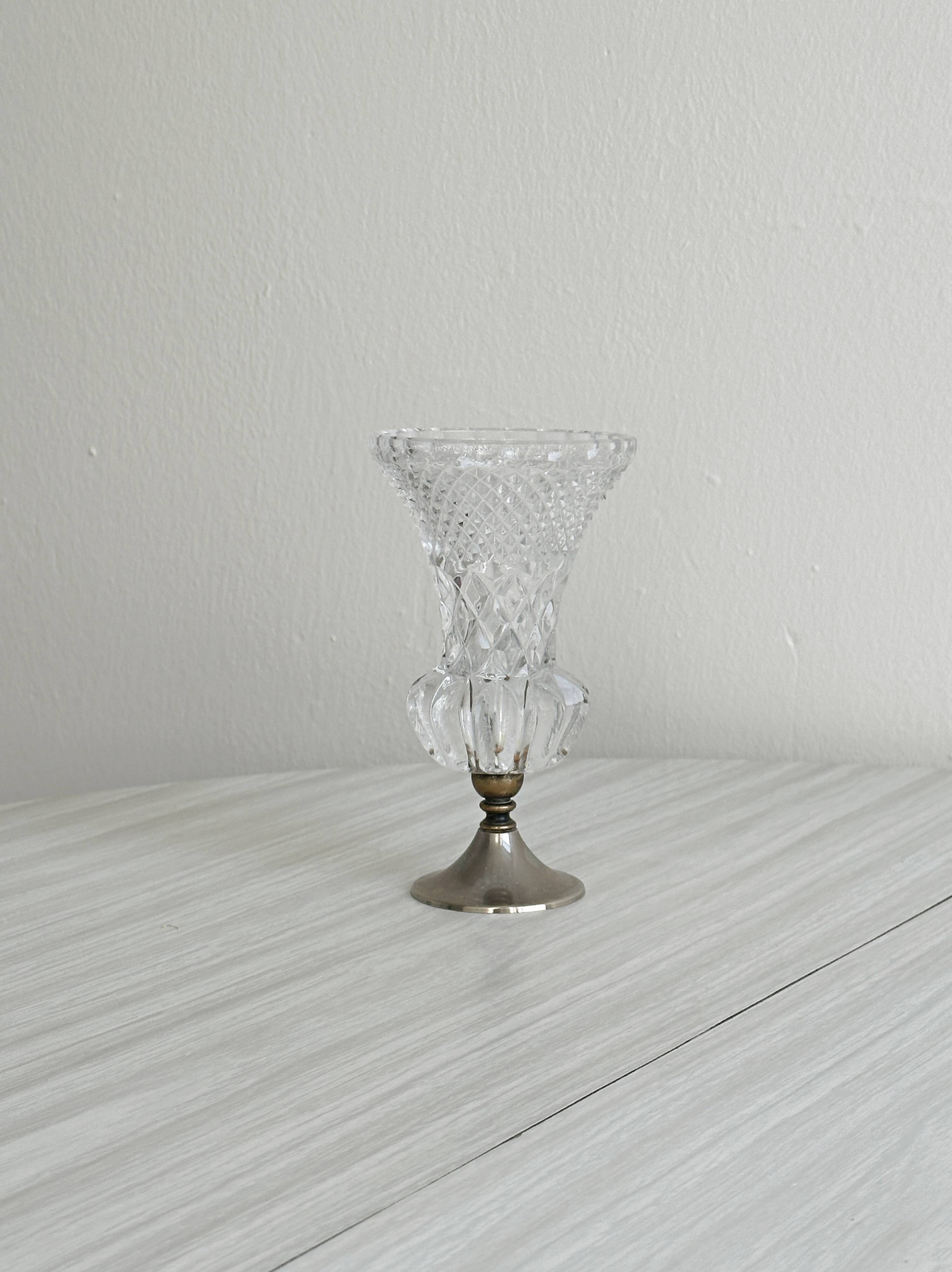 Small vase on a metal stand with thick glass.