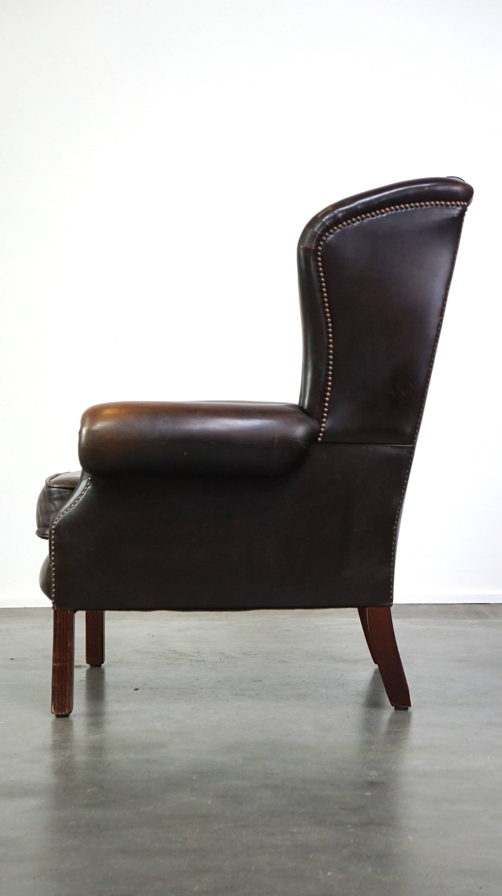 Chesterfield wing chair in dark brown leather with a luxurious appearance
