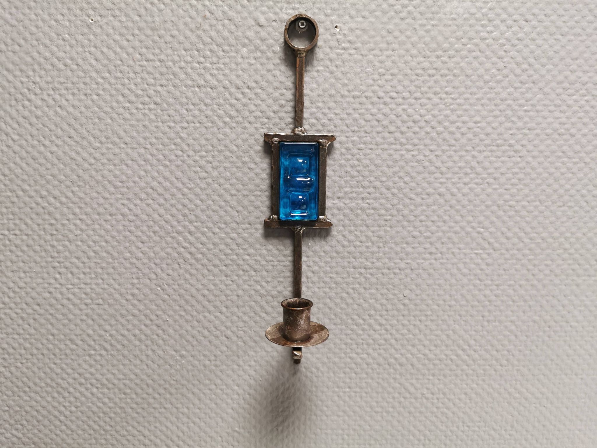 Wall-mounted candle holder in cast iron and hard pressed blue glass.
