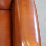 Correct, comfortable, luxurious English-style wingback armchair made of cognac-colored cow leather