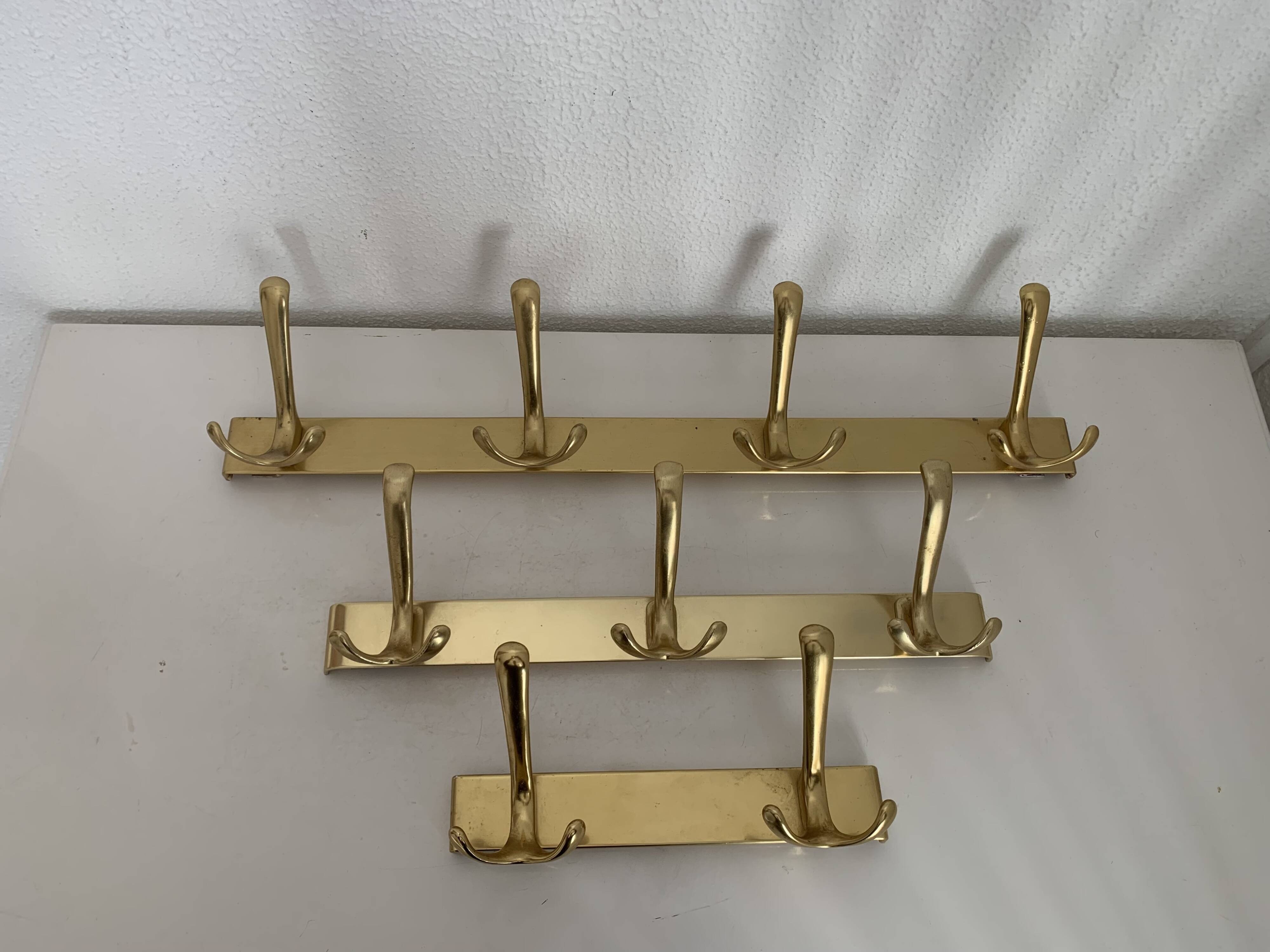 Three vintage 1960s gold coat racks with 4, 3 and 2 hooks