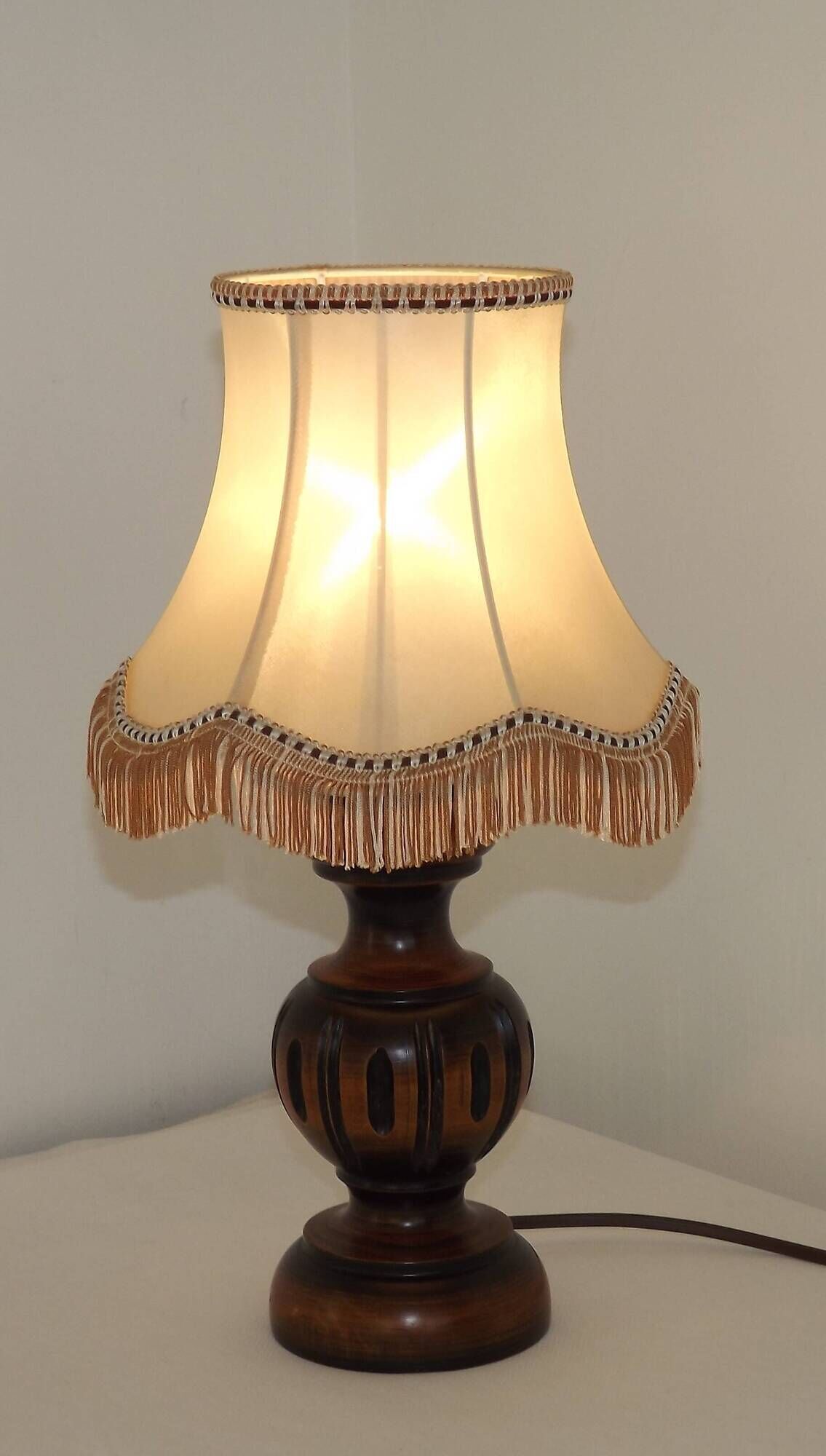 Mid-century French table lamp made of turned carved wood with a fringed shade.