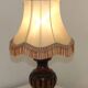 Mid-century French table lamp made of turned carved wood with a fringed shade.