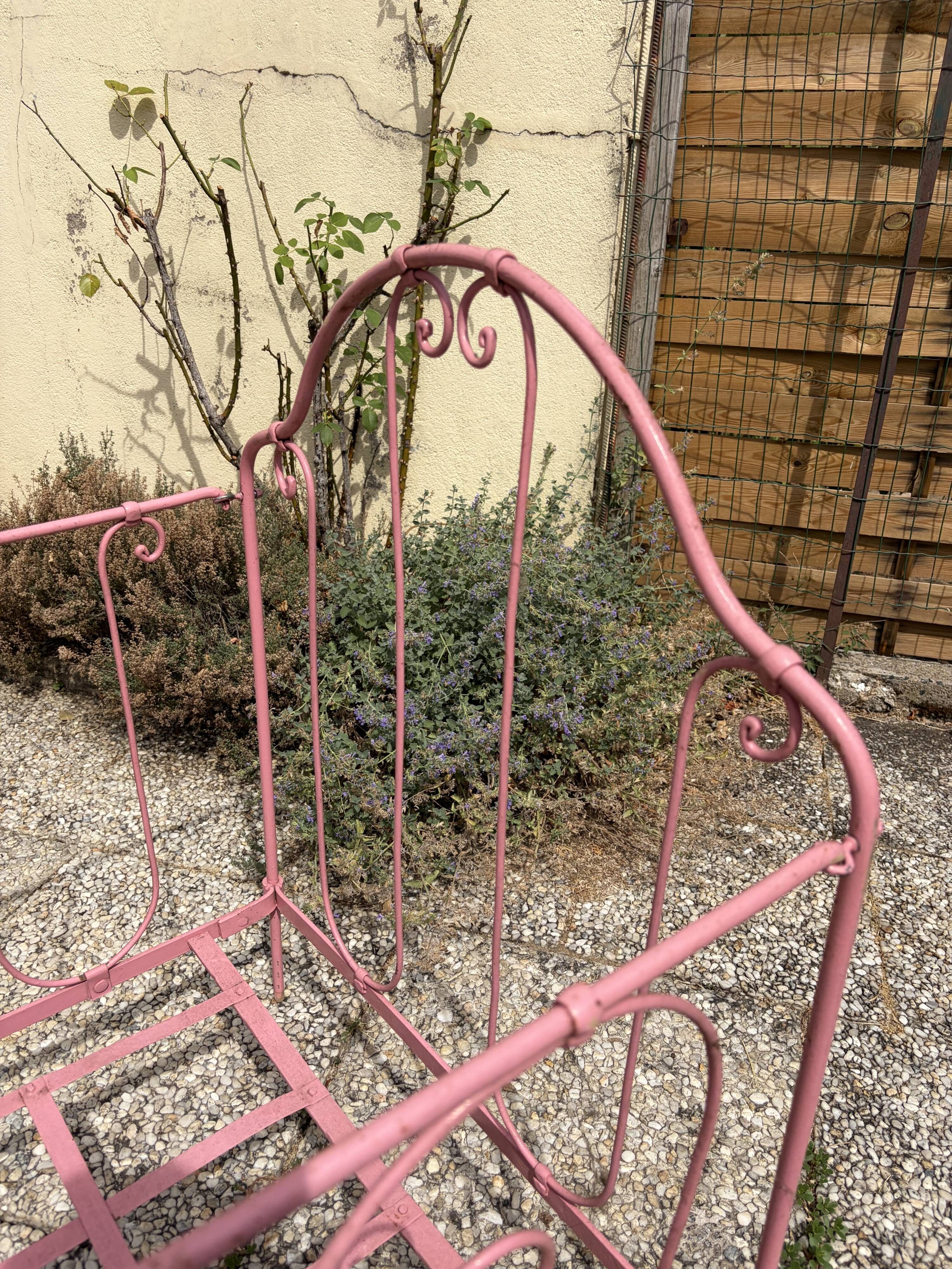 Old iron bed for children, painted pink with scrolls, romantic style.