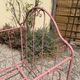 Old iron bed for children, painted pink with scrolls, romantic style.