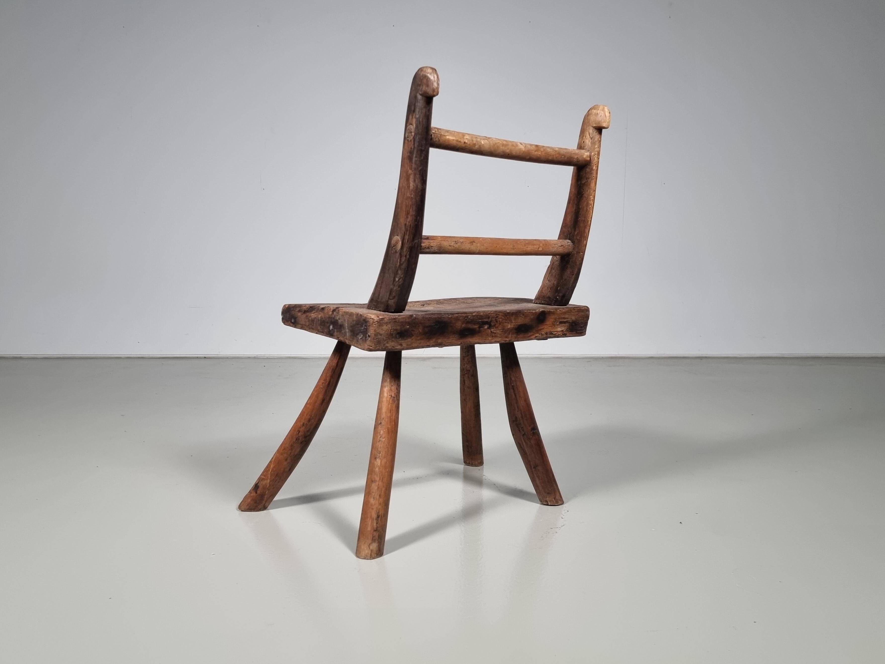 Rustic Wabi-Sabi style accent chair in dark curved hardwood, 1900s.