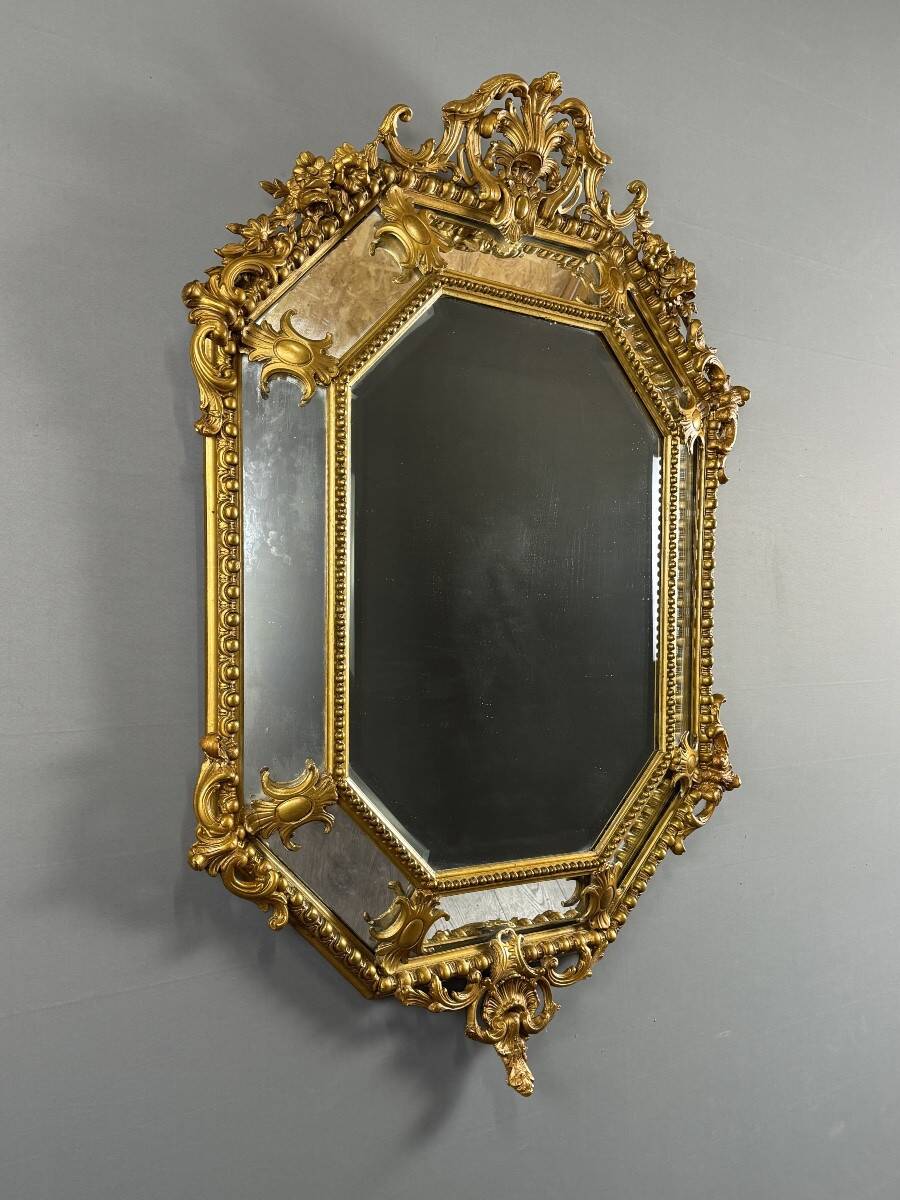 Antique octagonal mirror in richly carved gilded wood, Louis XV style.