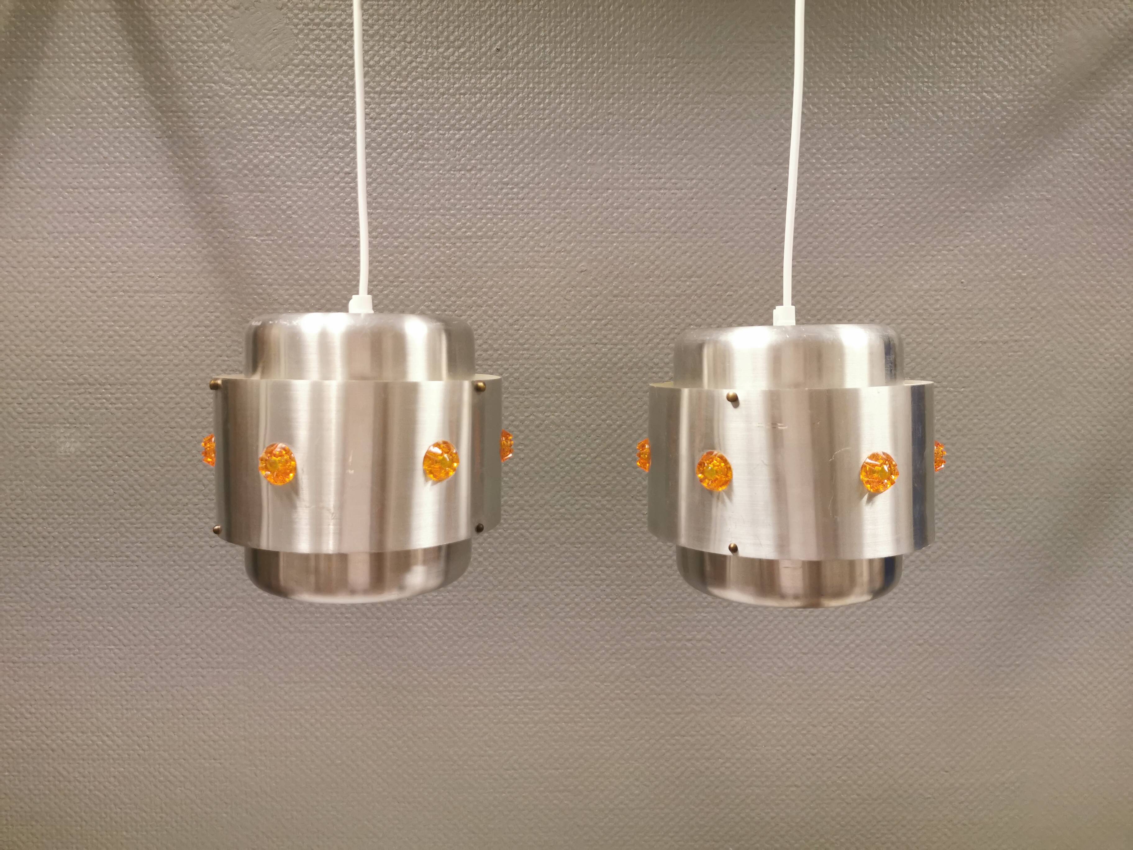 Two Space-Age hanging lamps, in silver-coloured aluminium with orange prisms.