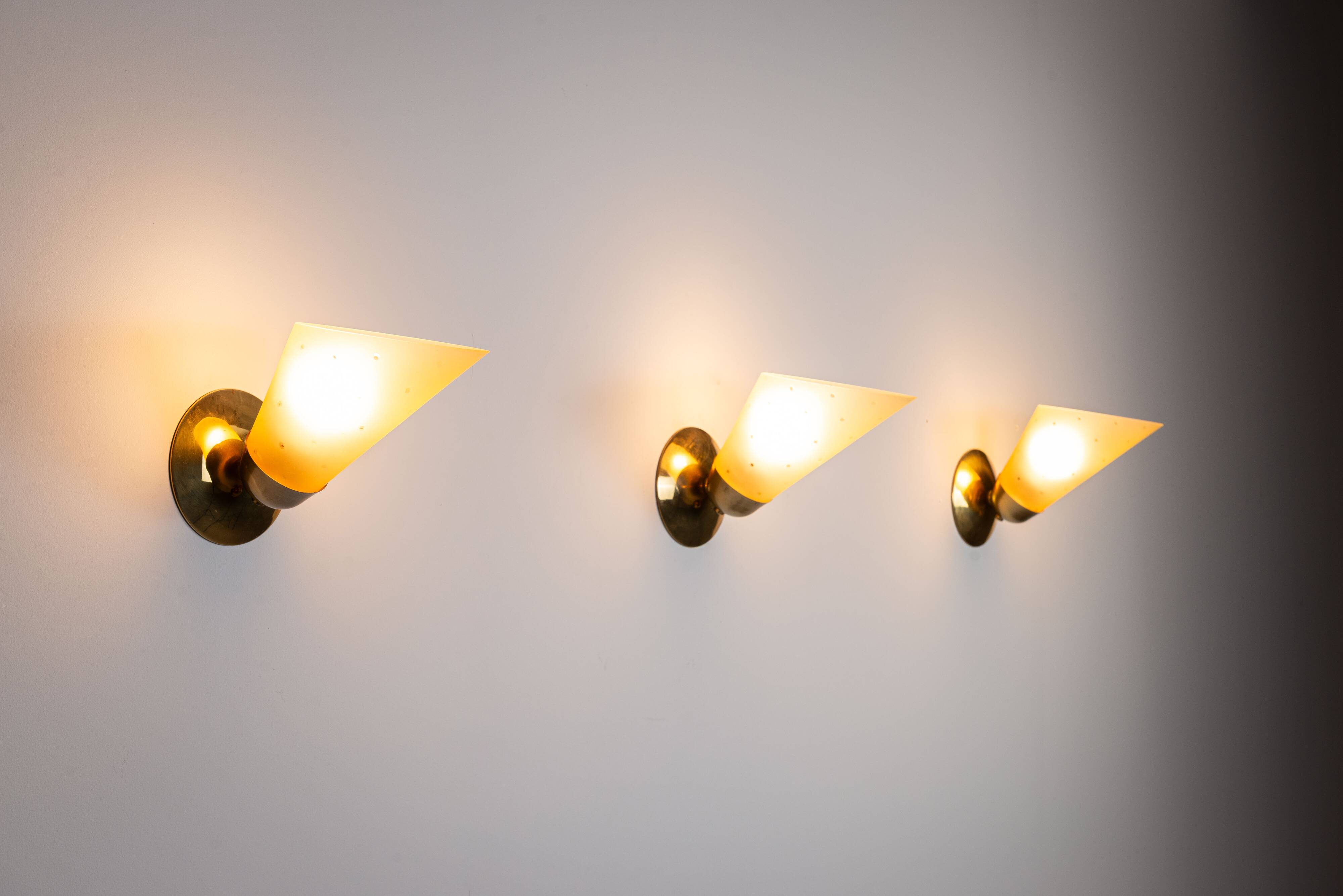 Set of three brass sconces with decorated yellow glass shades
