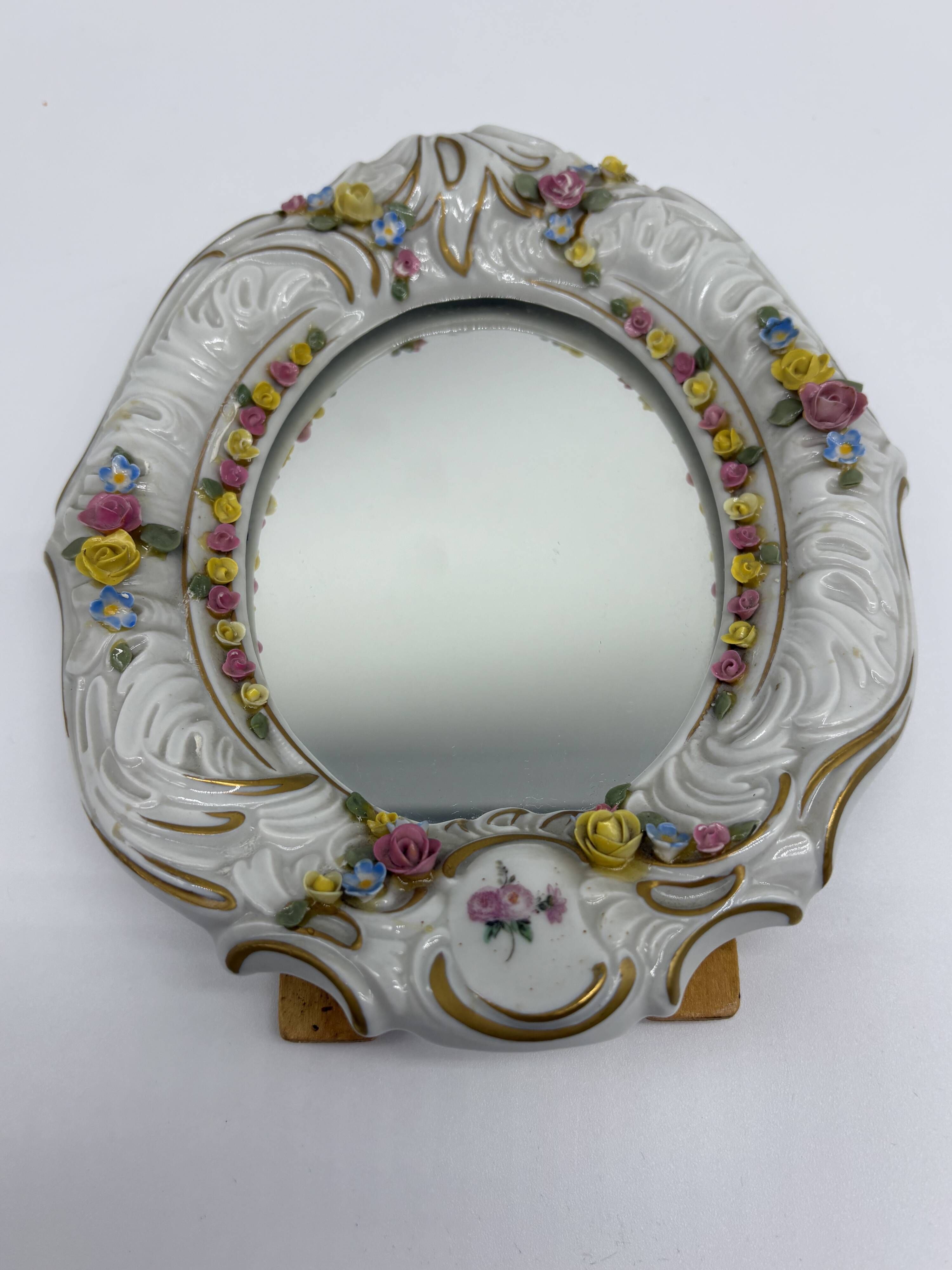 Antique porcelain mirror from Dresden with relief flowers and rococo decoration.