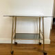 Vintage brass and smoked glass dessert trolley on wheels.