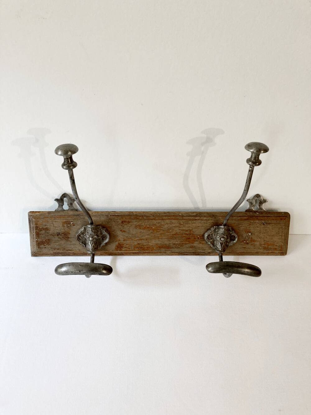 Pair of antique wrought iron coat hooks mounted on a wooden panel, 19th century