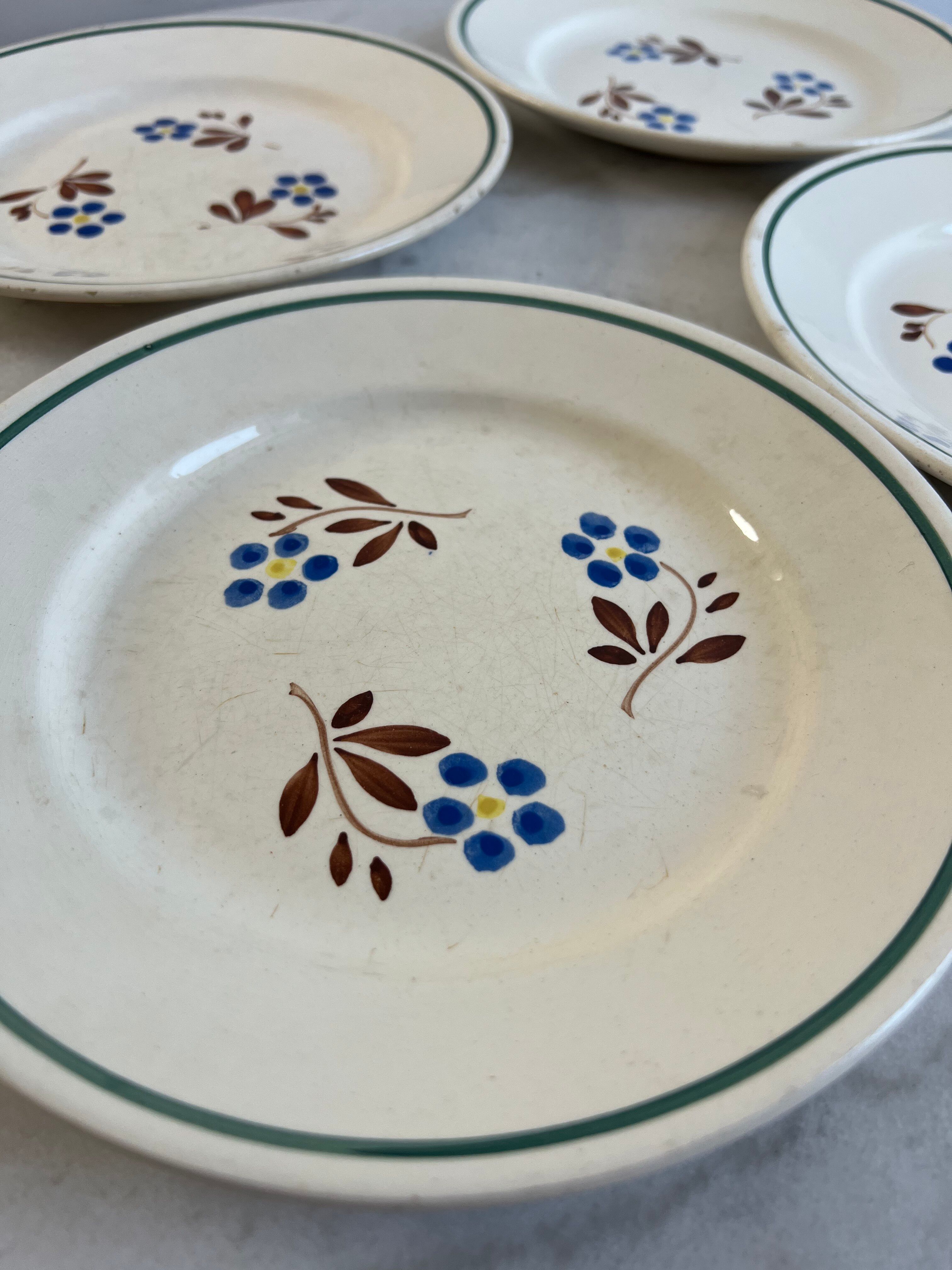 Set of 4 small flat plates with floral designs.