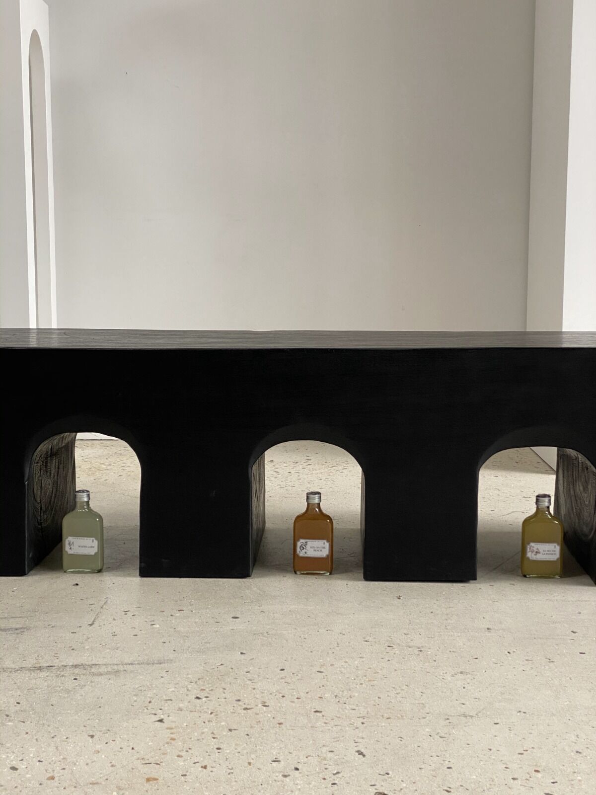 Black solid monoxyl wood bench carved into 3 arches