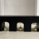 Black solid monoxyl wood bench carved into 3 arches