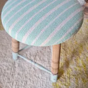 Antique tripod stool with blue striped seat.
