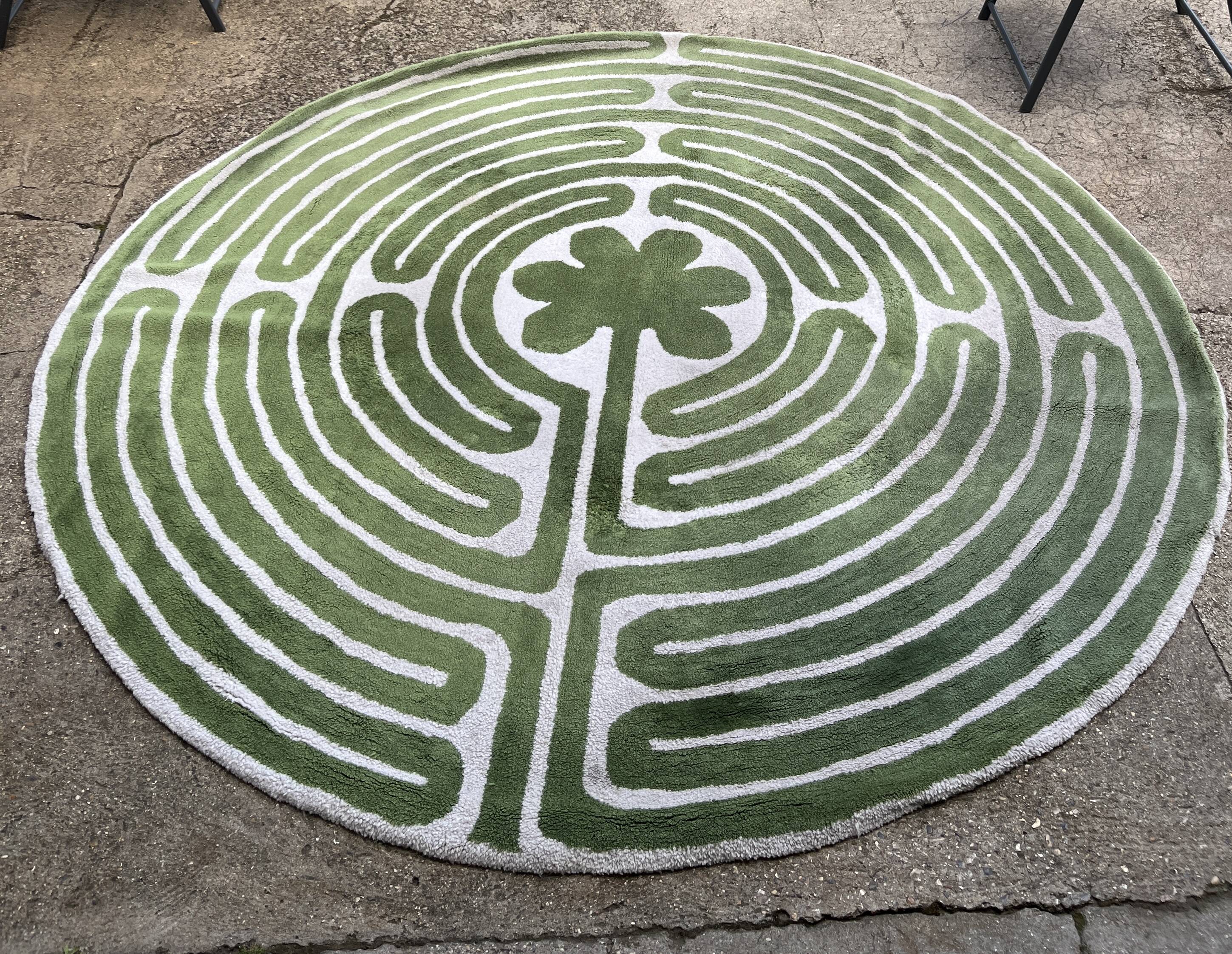 Circular rug with green decor on a cream background from the Labyrinth.