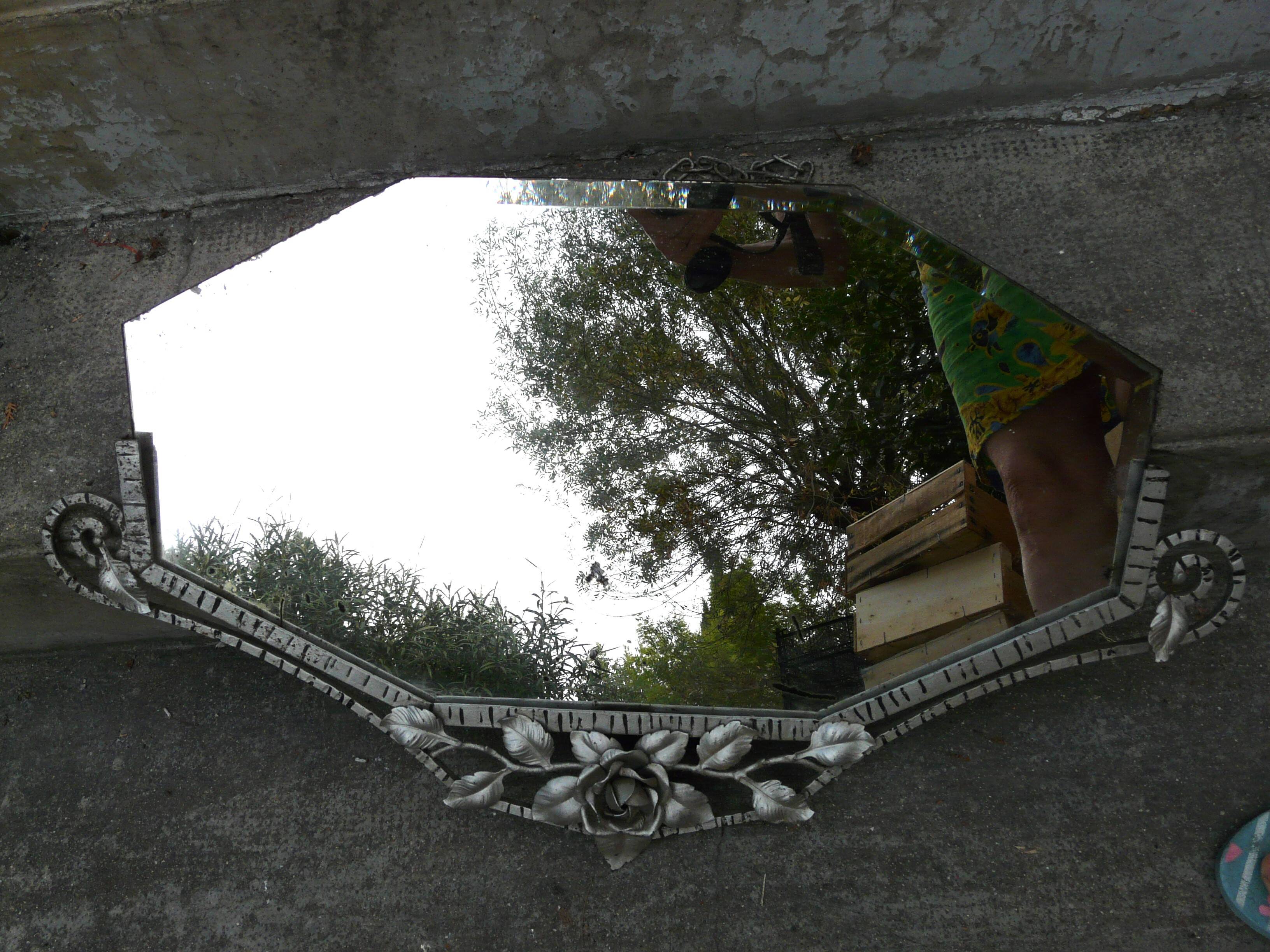 Beveled mirror with art-deco wrought iron frame and floral decor with hanging chain