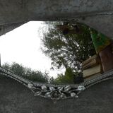 Beveled mirror with art-deco wrought iron frame and floral decor with hanging chain