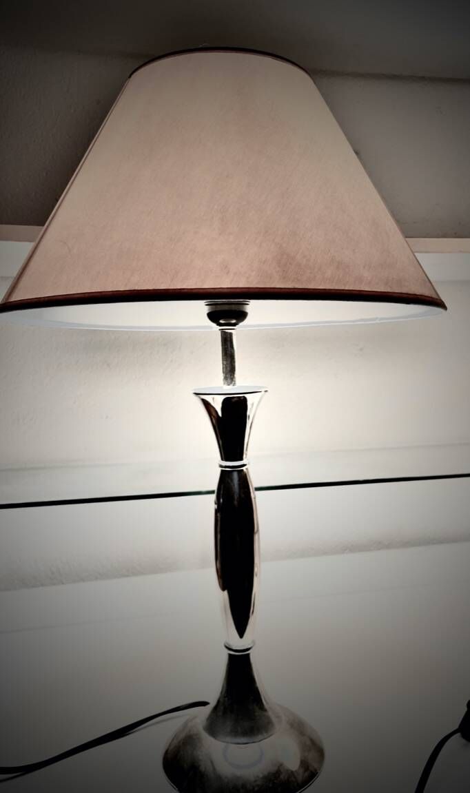 Contemporary table lamp in polished chrome with a conical fabric shade.