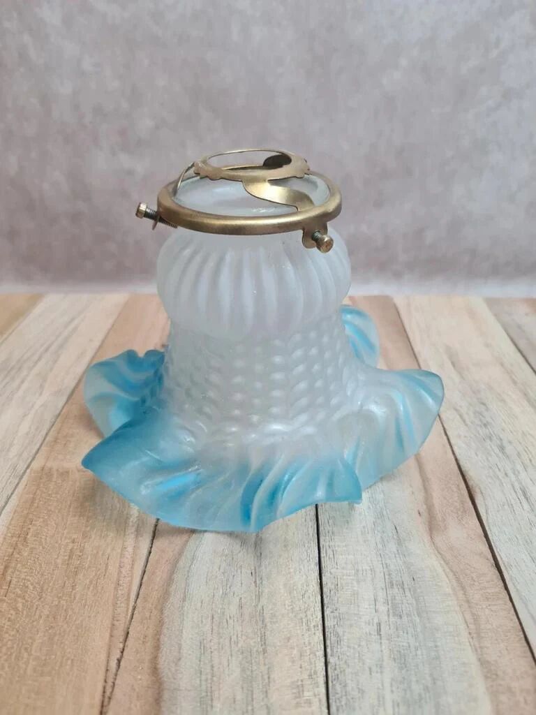 An antique lampshade in frosted glass with delicate blue edges.