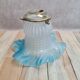 An antique lampshade in frosted glass with delicate blue edges.
