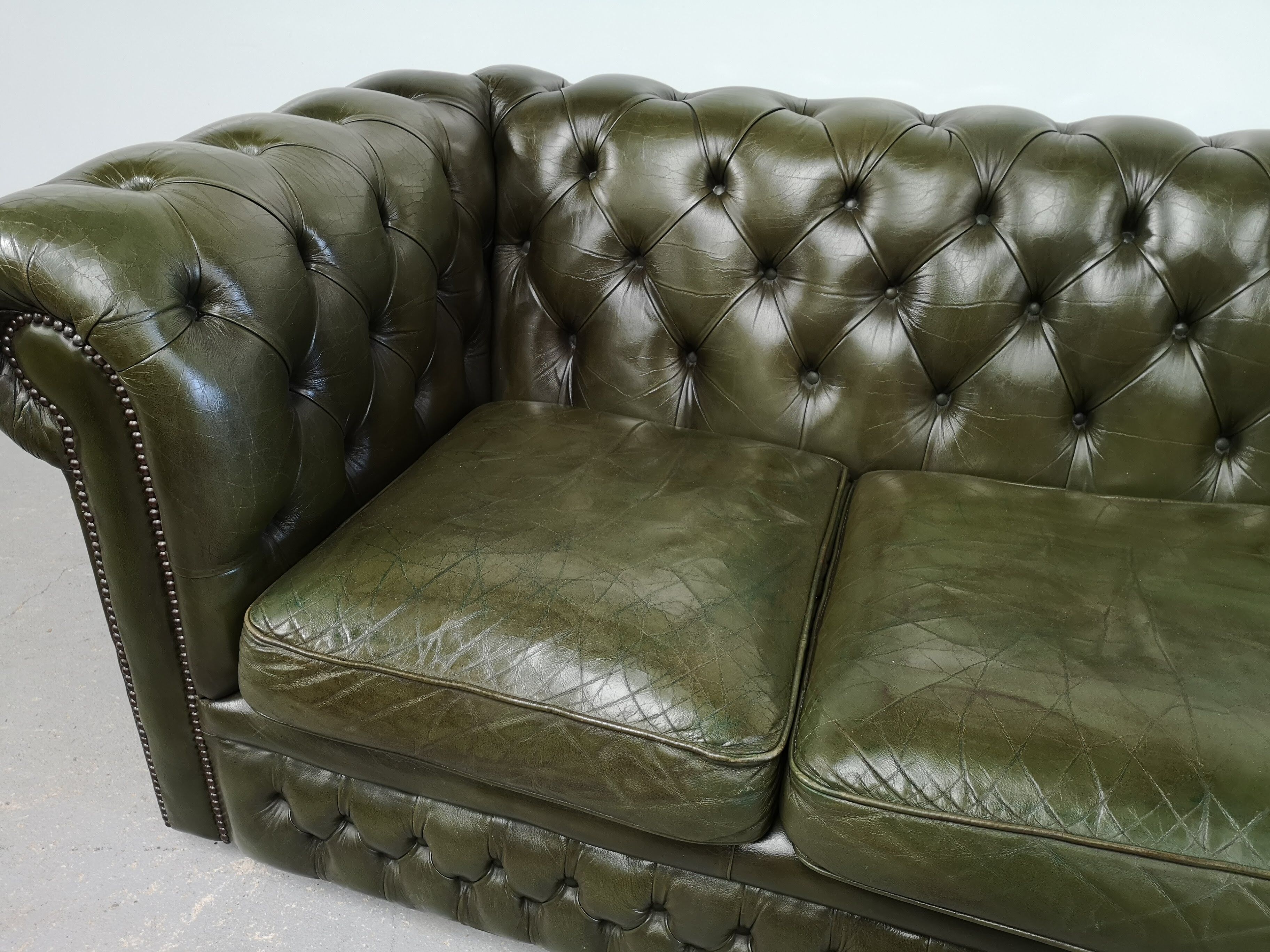 Three-seater green leather Chesterfield sofa