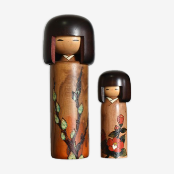 Pair of japanese dolls. kokeshi usaburo, camellia floral decoration, engraved and painted by hand.