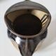 Stoneware jug with deep black drips on a sandy background.
