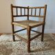 Antique corner chair by the fire with turned wood and straw seat.
