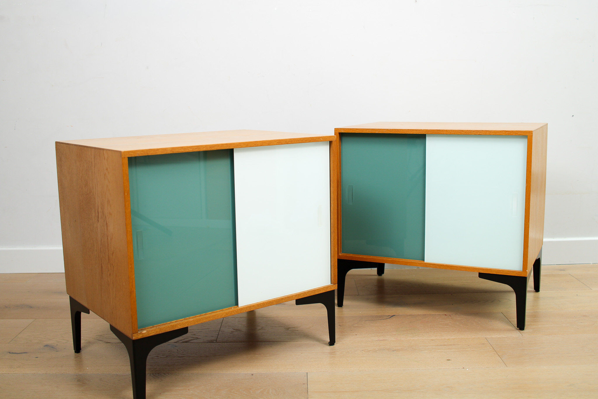 A pair of vintage mid-century bedside tables with glass sliding doors