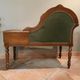 Antique carved wooden bench with green upholstered seat and backrest.