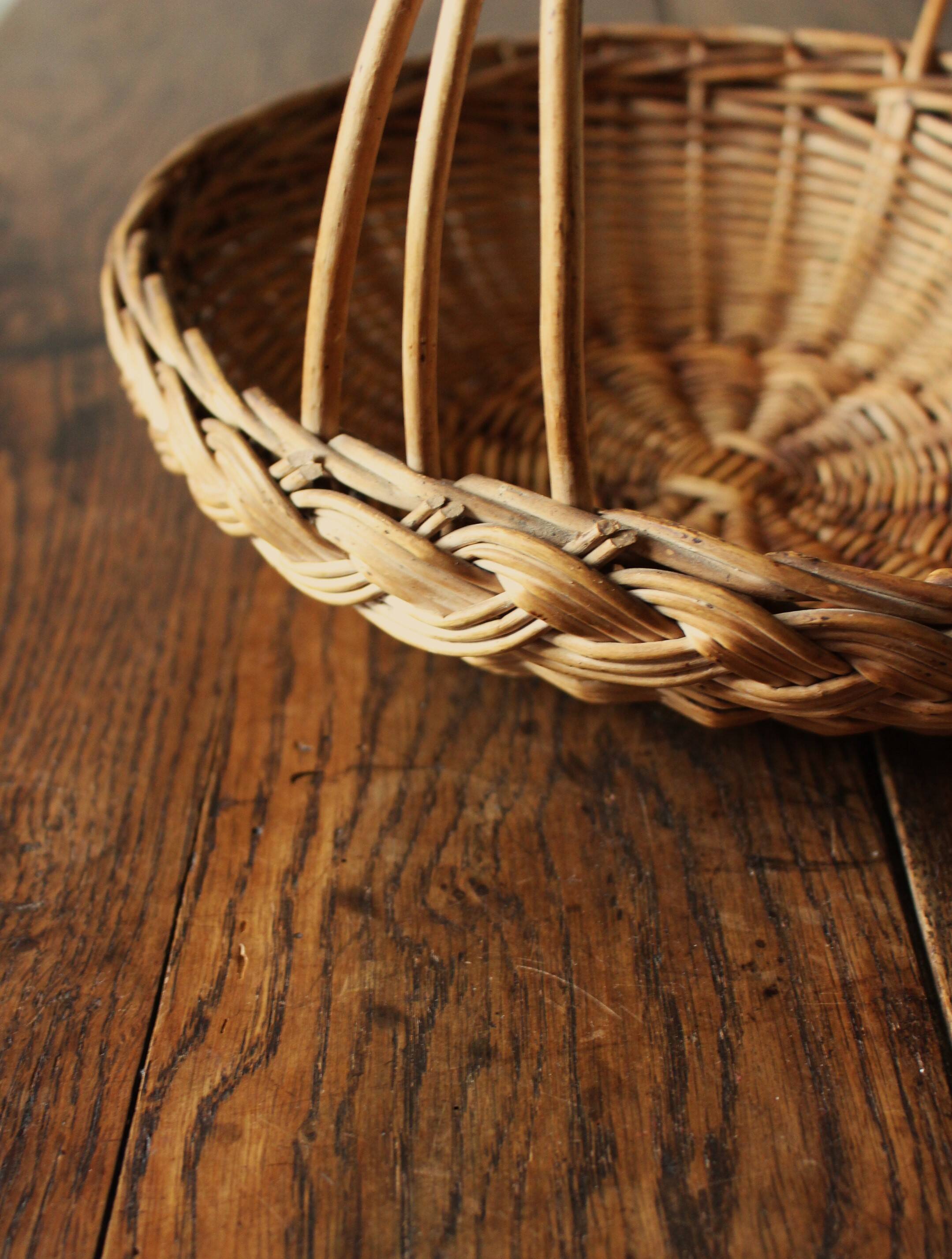Round wicker basket with a rigid handle.
