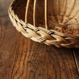 Round wicker basket with a rigid handle.