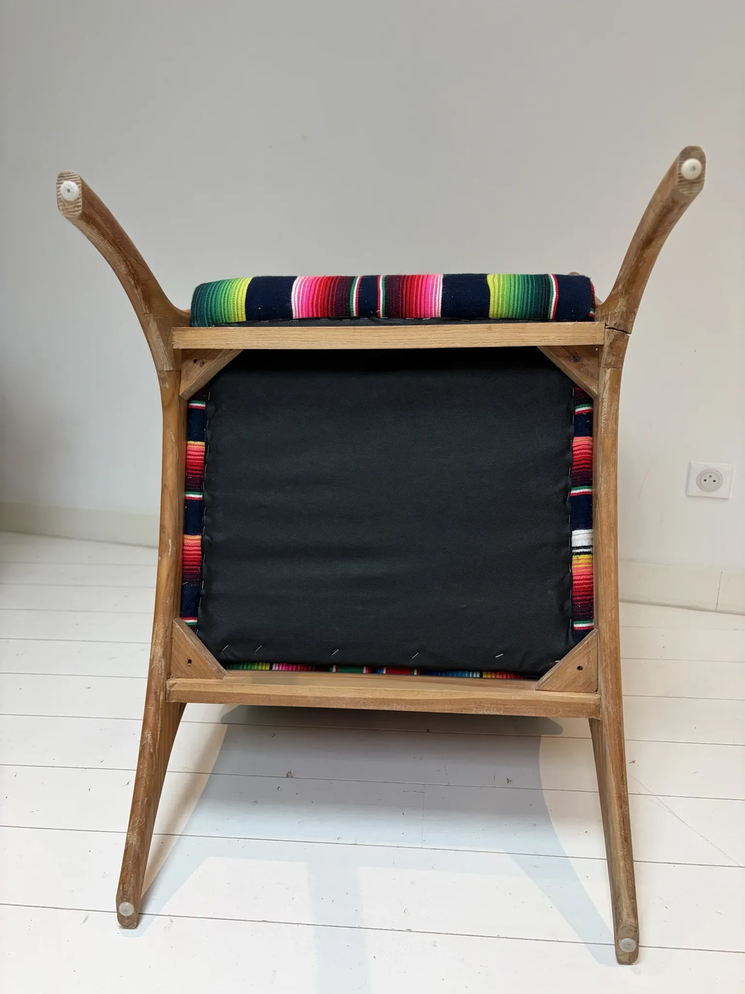 Scandinavian-style armchair in curved wood and colourful striped fabric.