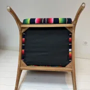 Scandinavian-style armchair in curved wood and colourful striped fabric.
