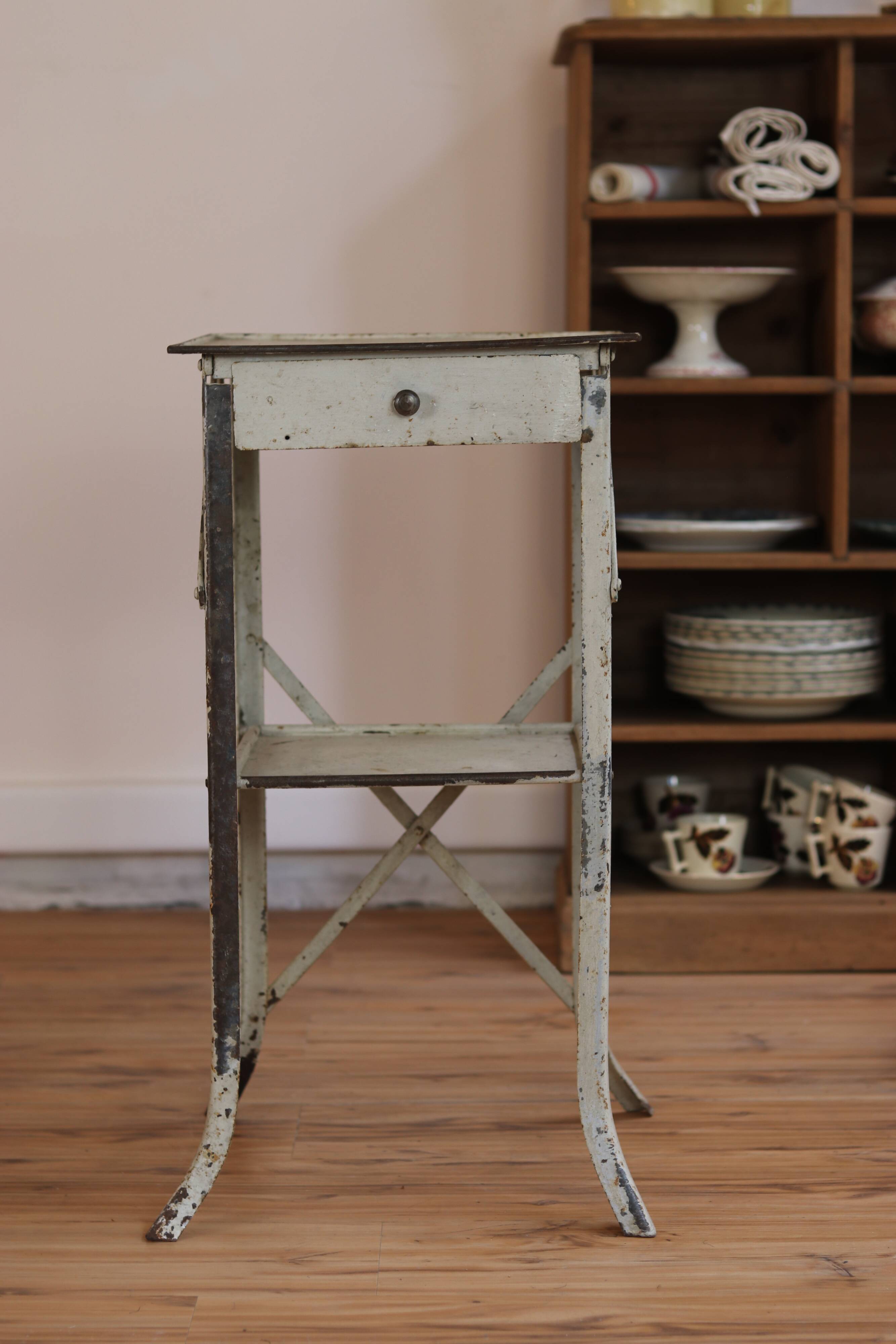 Painted metal side table, patinated white, with a drawer and two shelves