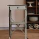 Painted metal side table, patinated white, with a drawer and two shelves