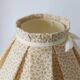 Table lamp with a carved wooden base and pleated lampshade