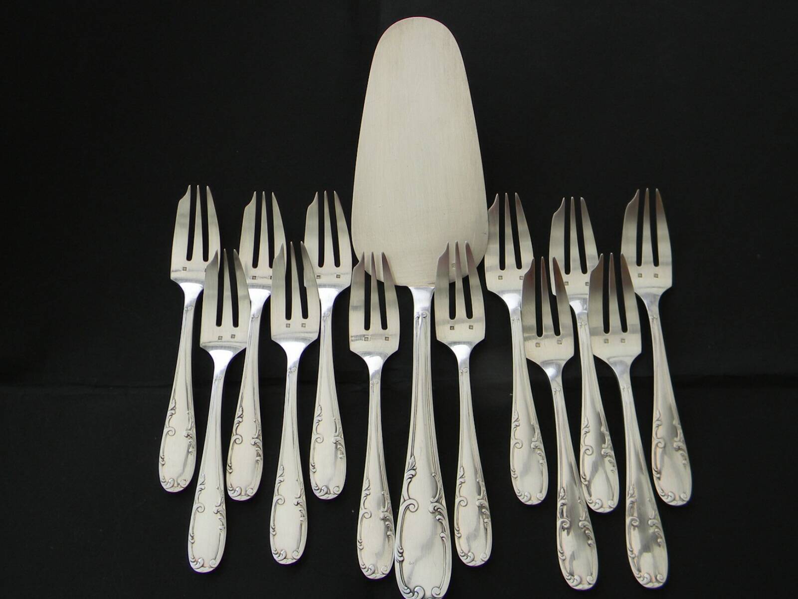 12 cake forks and a silver metal server.