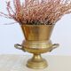 Vintage brass cache-pot on a stand with handles, classic decor.