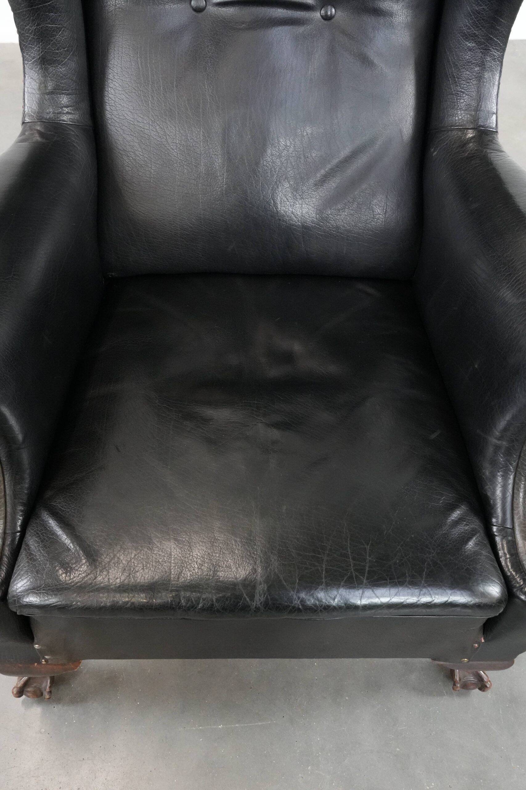 Antique black English cow leather wingback armchair from the 19th century