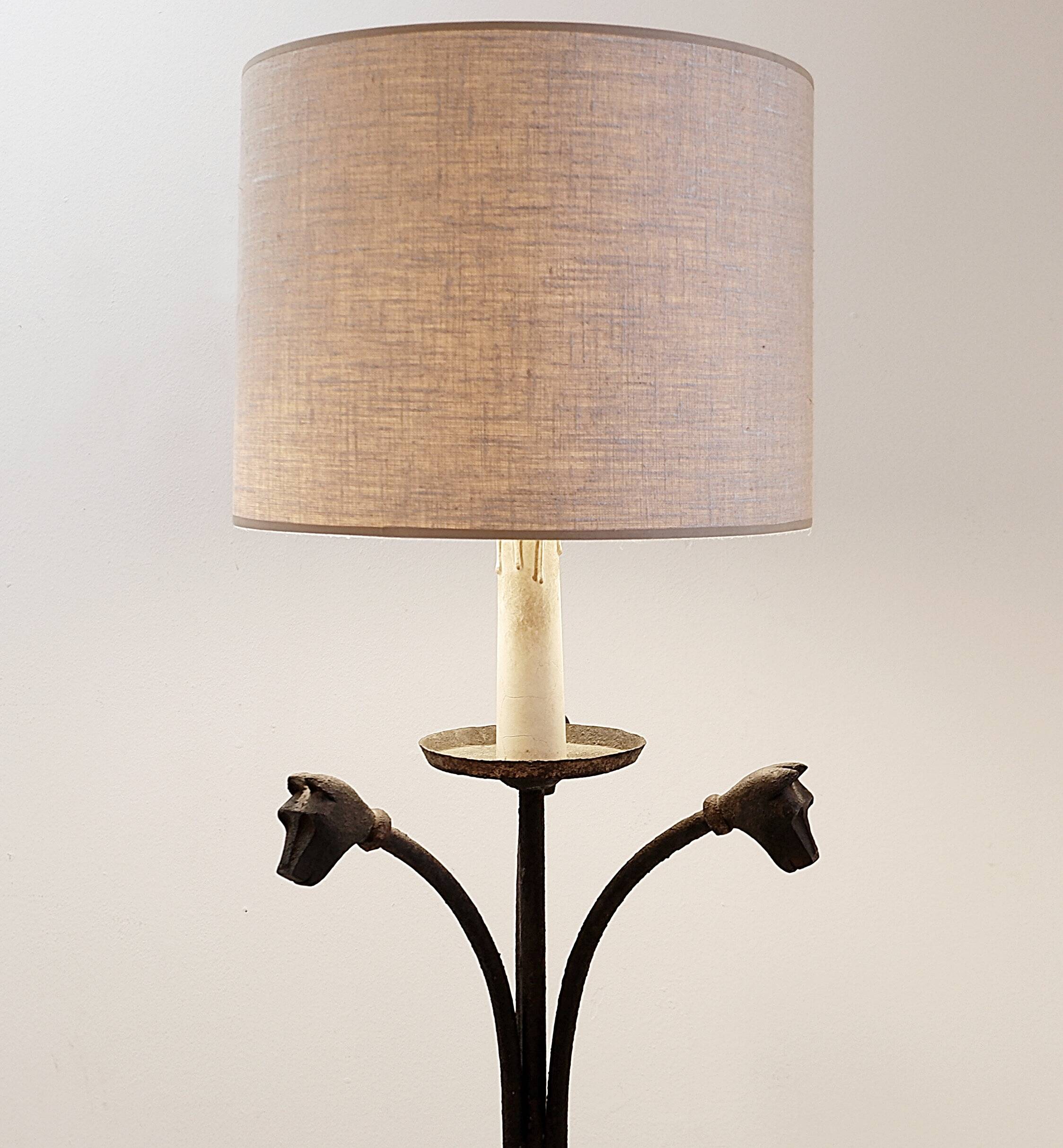 Wrought iron tripod floor lamp decorated with stylized animal heads
