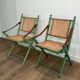 Paire de chaises safari pliantes façon faux-bambou patiné, dossiers et assises cannées et repose-bras en cuir