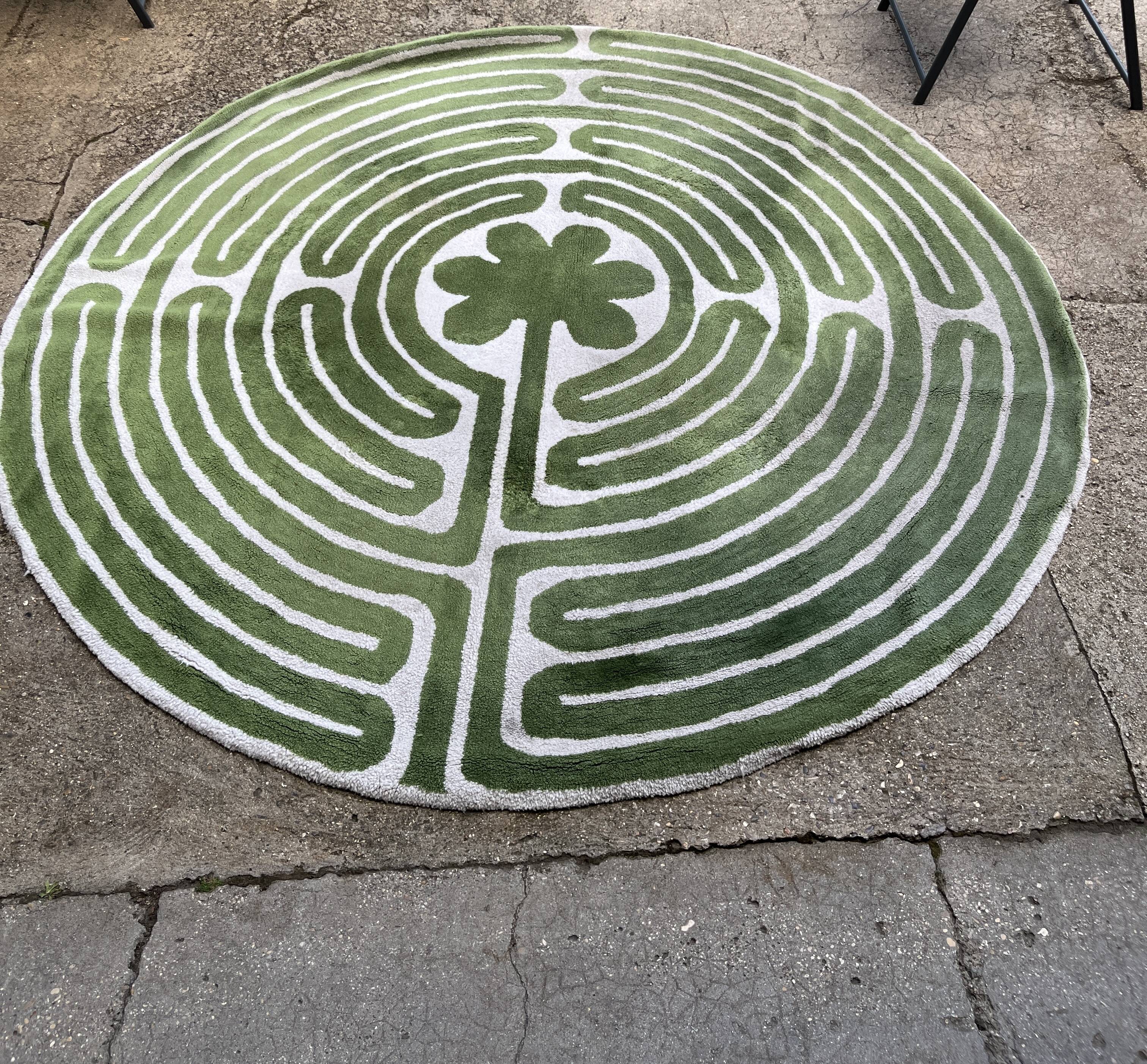 Circular rug with green decor on a cream background from the Labyrinth.